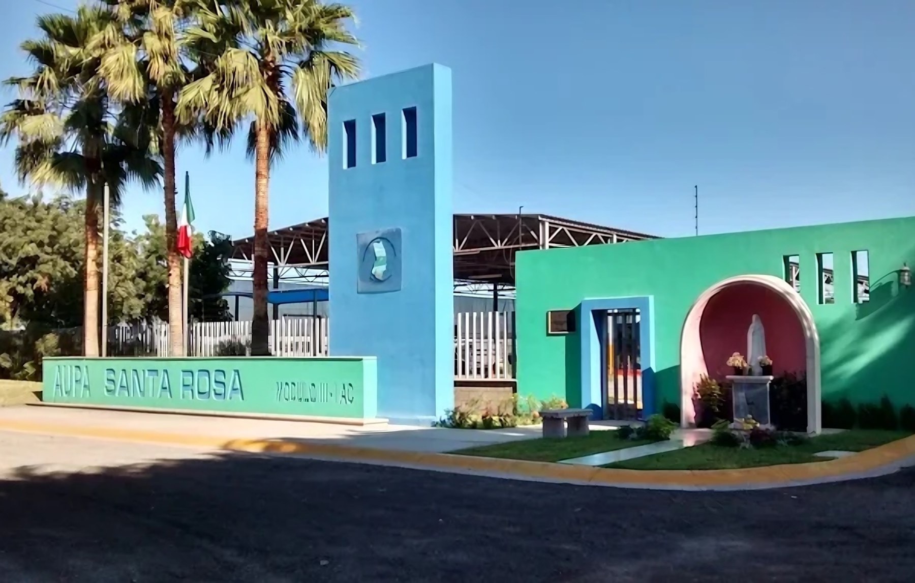 Patio y oficinas de AUPA Santa Rosa Módulo III-1: letrero, torre y acceso con arco.